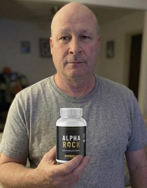 An adult man holding a bottle of the Alpha Rock supplement at home